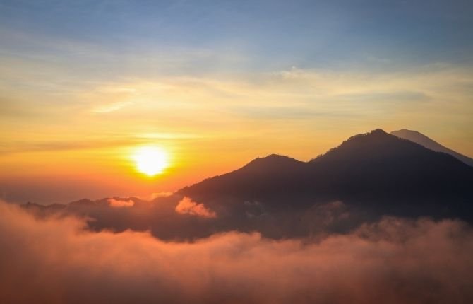 Sunrise over Mount Batur volcano with clouds below the summit